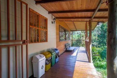 a porch of a house with four trash cans at Cabaña de montaña La Magnolia, Cerro de la Muerte De La Cañuela Cloud Forest in Tres de Junio