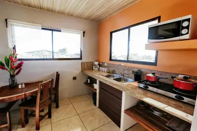 a kitchen with a sink and a table and two windows at Casa Monarca - Monteverde in Monteverde Costa Rica