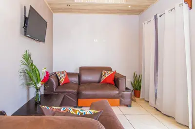 a living room with a leather couch and a tv at Casa Monarca - Monteverde in Monteverde Costa Rica
