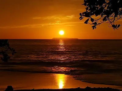 a sunset on the beach with the sun setting at The Sunset Tucano Lodge in Drake