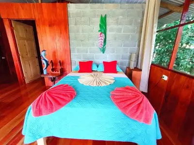 a bedroom with a blue bed with red pillows at The Sunset Tucano Lodge in Drake