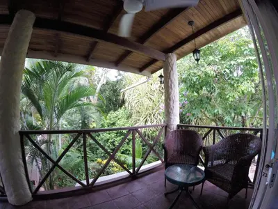 a porch with two chairs and a table on it at The Falls at Manuel Antonio in Manuel Antonio