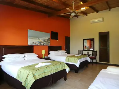 a hotel room with three beds with orange walls at The Falls at Manuel Antonio in Manuel Antonio