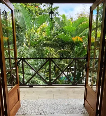 an open door to a garden with palm trees at The Falls at Manuel Antonio in Manuel Antonio