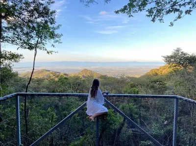 a woman sitting on a railing looking out over the mountains at Domos Mirador Romantic Private Honeymoon Glamping in Miramar