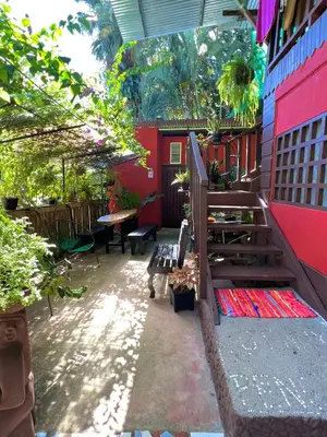 a patio with a bench and a red building at Pura Vida Hostel in Montezuma