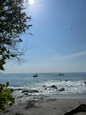 two boats in the water on the beach at Pura Vida Hostel in Montezuma