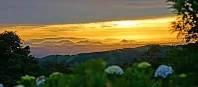a sunset over a mountain range with clouds at El Establo Mountain Hotel in Monteverde Costa Rica