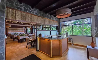 a restaurant with a bar and tables and windows at El Establo Mountain Hotel in Monteverde Costa Rica