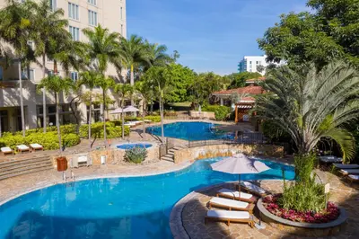 a pool at a hotel with lounge chairs and an umbrella at InterContinental Costa Rica at Multiplaza Mall by IHG in San José