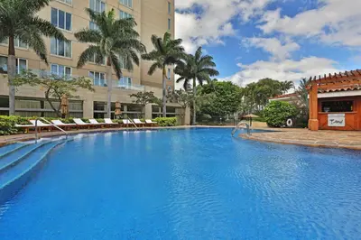 a large swimming pool with chairs and a building at InterContinental Costa Rica at Multiplaza Mall by IHG in San José
