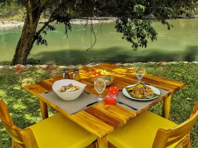 a wooden table with plates of food and wine glasses at Pacuare Lodge by Böëna in Bajo Tigre