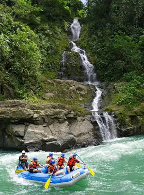 a group of people in a raft in a river with a waterfall at Pacuare Lodge by Böëna in Bajo Tigre