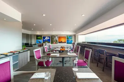 a restaurant with a table and chairs and a counter at Crowne Plaza San Jose La Sabana by IHG in San José