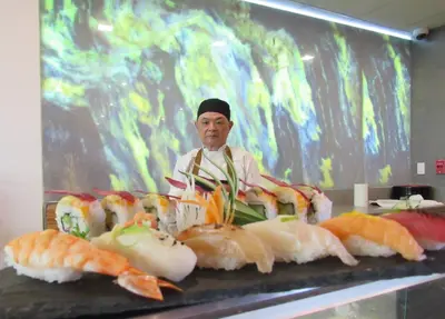 a man is standing behind a table of sushi at Crowne Plaza San Jose La Sabana by IHG in San José