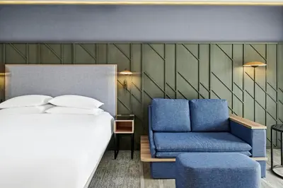 a bedroom with a bed and a blue chair at Courtyard by Marriott San Jose Escazu in San José