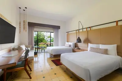a hotel room with two beds and a desk and a table at Los Sueños Marriott Ocean & Golf Resort in Jacó