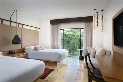 a bedroom with two beds and a table and a couch at Los Sueños Marriott Ocean & Golf Resort in Jacó
