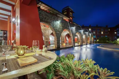 a restaurant with a table with wine glasses next to a pool at Los Sueños Marriott Ocean & Golf Resort in Jacó