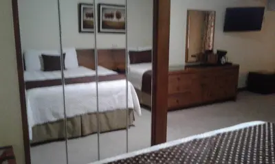 a reflection of a bedroom with two beds and a mirror at Hotel Villa Tournon in San José