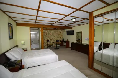 a bedroom with two beds and a desk with a television at Hotel Villa Tournon in San José