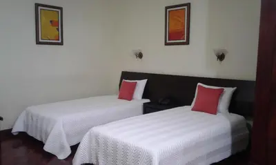 two beds in a room with white and red pillows at Hotel Villa Tournon in San José