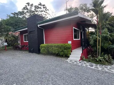 a red house with a red door and a driveway at Residencias Arenal in Fortuna