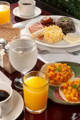 a table with plates of food and glasses of orange juice at Studio Hotel Boutique in San José
