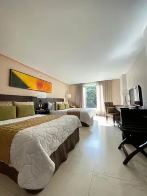 a hotel room with two beds and a desk at Studio Hotel Boutique in San José