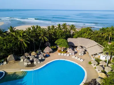 an aerial view of a resort with a swimming pool and the ocean at Occidental Tamarindo - All Inclusive in Tamarindo
