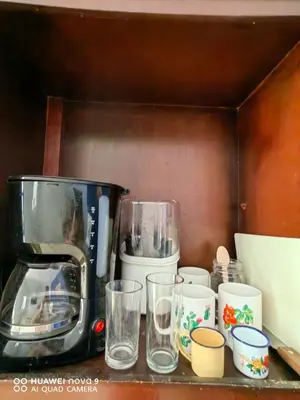 a shelf with cups and a coffee maker on it at Casa Mariana in Alajuela City