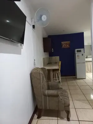 a living room with a chair and a tv at Casa Mariana in Alajuela City