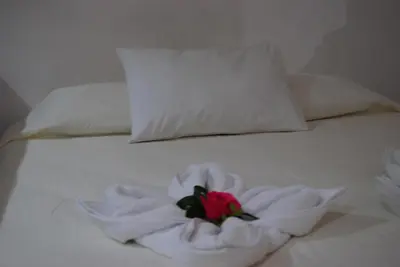 a white bed with a red rose on it at Casa Mariana in Alajuela City