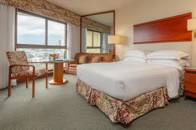 a bedroom with a large bed and a living room at Barceló San José in San José