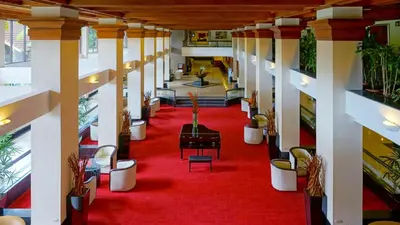 a hallway with a red carpet and a room with potted plants at Barceló San José in San José