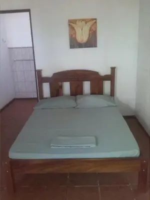 a bed in a room with a wooden head board at Tiquisia Lodge in Curubandé