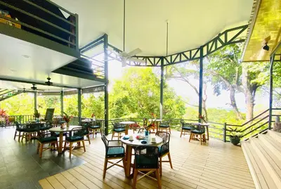 a restaurant with tables and chairs on a deck at Villas en el Bosque in Ojochal