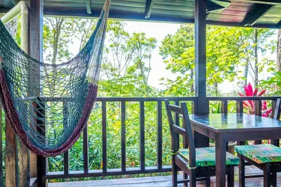 a hammock on a porch with a table and chairs at Villas en el Bosque in Ojochal