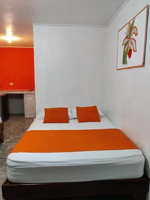 a bedroom with a large bed with orange sheets at Cabinas Maritza in Quebrada Ganado