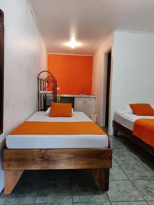 a bedroom with two beds and an orange wall at Cabinas Maritza in Quebrada Ganado