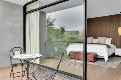 a bedroom with a bed and a balcony with a table at Quinta Esencia in Alajuela City