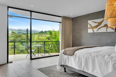 a bedroom with a bed and a balcony with a table at Quinta Esencia in Alajuela City