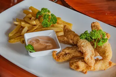 a plate of food with chicken tenders and french fries at Villas Fernanda in Fortuna