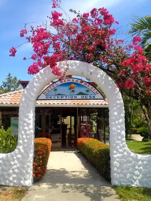 an arch with pink flowers in front of a building at Samara Beach Hotel in Sámara