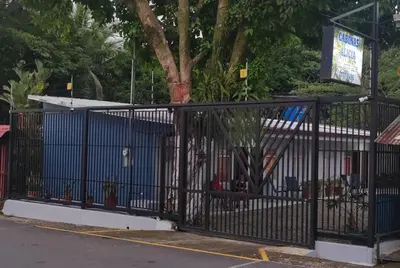 a black fence with a tree behind it at Cabinas Doña Alicia in Quepos
