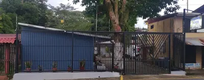 a blue gate with a tree in front of a building at Cabinas Doña Alicia in Quepos