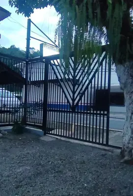 a black gate with a tree in front of it at Cabinas Doña Alicia in Quepos