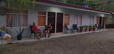 three people sitting on chairs outside of a building at Cabinas Doña Alicia in Quepos
