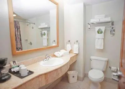 a bathroom with a sink and a toilet and a mirror at Sleep Inn Paseo Las Damas in San José