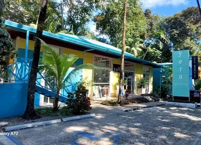a blue and yellow building with palm trees in front at Hotel Plaza Yara in Manuel Antonio